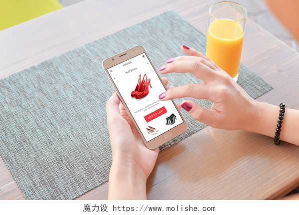 女子用智能手机在网上购物女人在网上买红鞋。移动应用程序或网站在屏幕上。背景表和果汁.